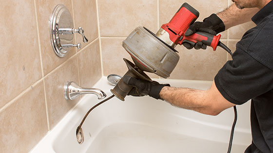 Plumber cleaning a bathtub drain